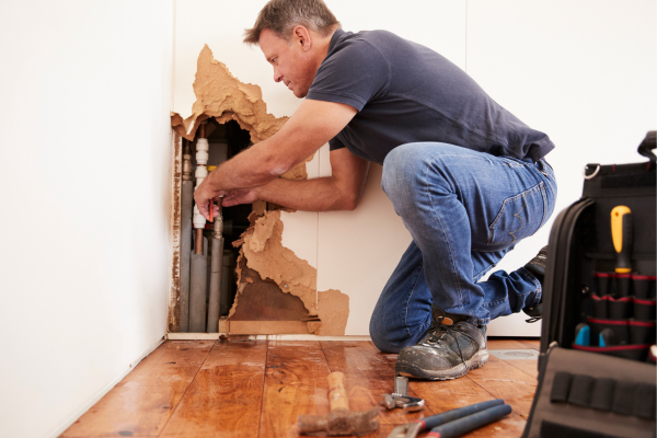 Plumber fixing a burst pipe to prevent water damage caused by freezing during the winter months