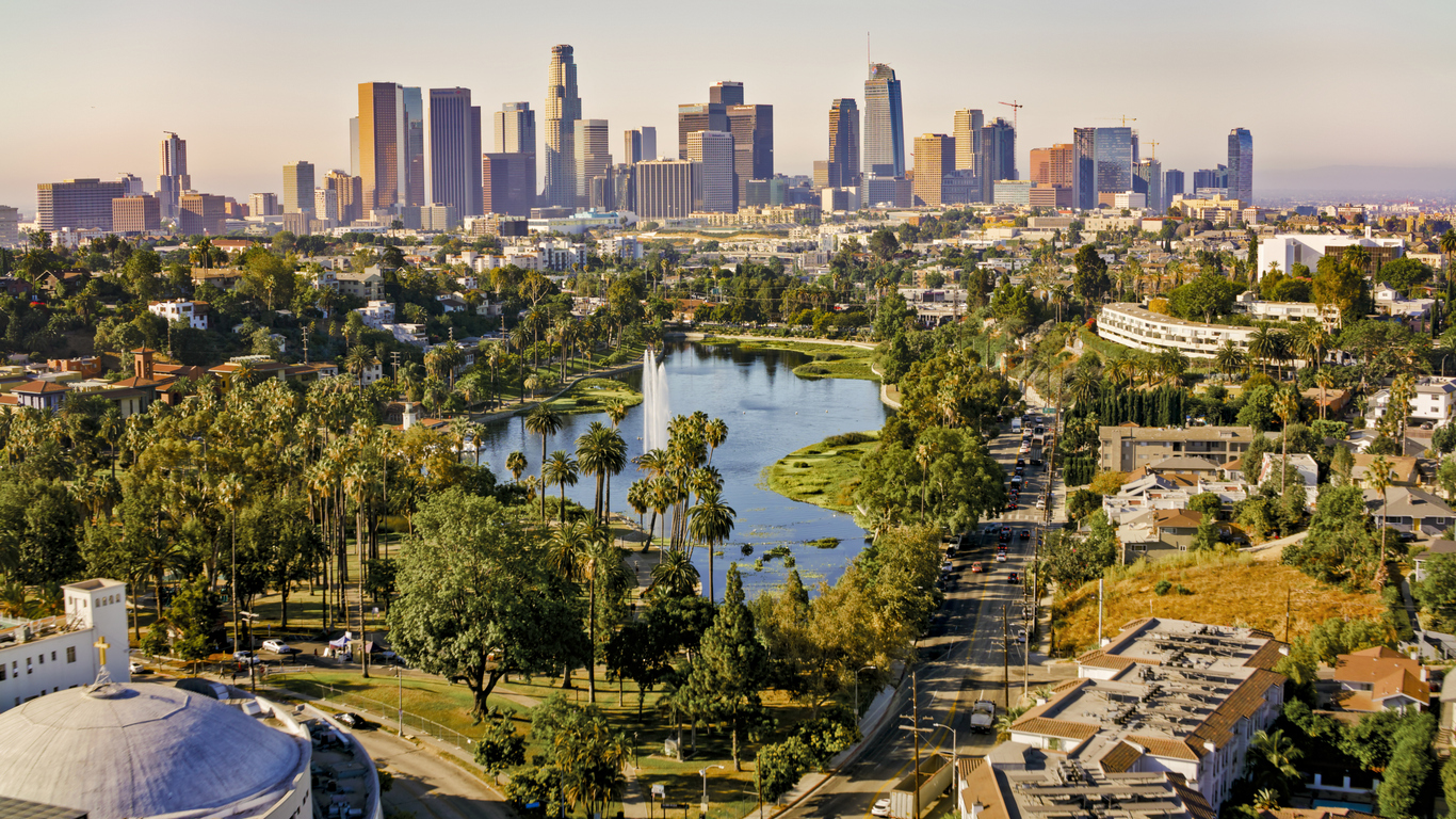 Scenic view of downtown Los Angeles on a sunny day, with parks and palm trees in the foreground.