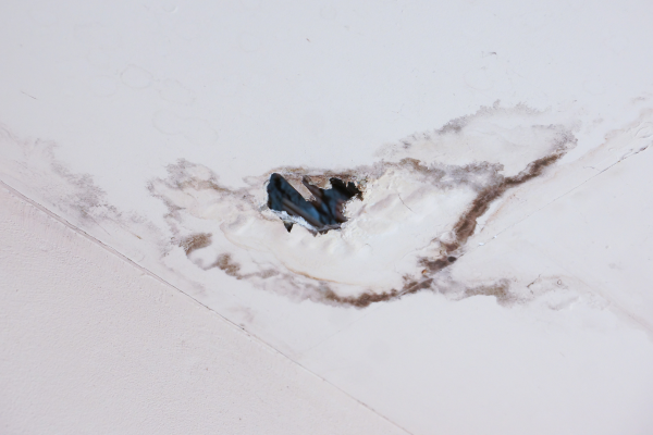 Close-up of ceiling with water stains and peeling paint.