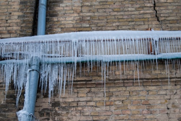 Frozen pipes with icicles hanging, showing winter water damage risks.