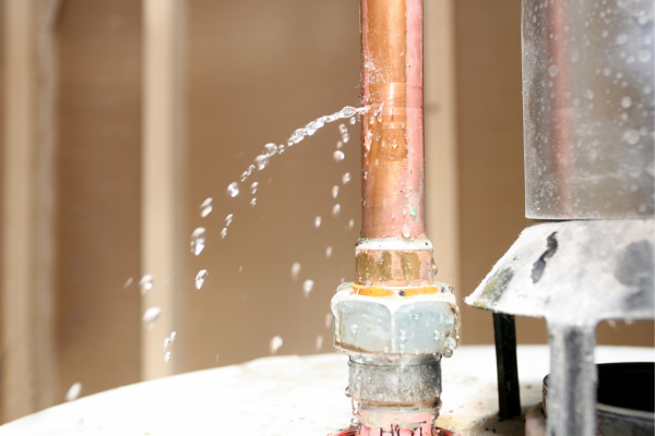 Close-up of a copper pipe with water leaking from a crack.